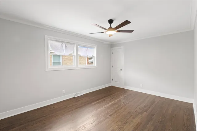 a view of an empty room with wooden floor and window