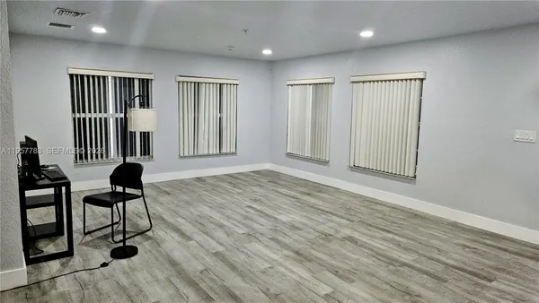 a view of an empty room with wooden floor and windows