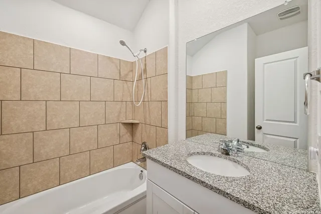 a bathroom with a granite countertop sink and a bathtub