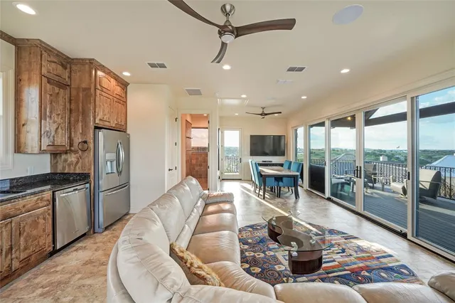 a living room with stainless steel appliances granite countertop furniture a fireplace and a view of kitchen