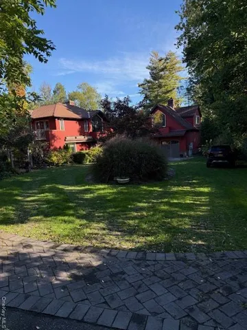 a view of a big yard with potted plants and large trees