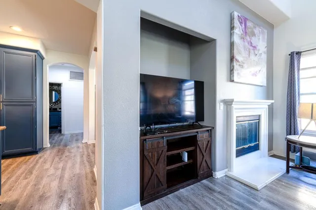 a view of a livingroom with wooden floor a flat screen tv and a fireplace