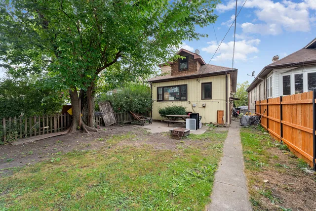 a view of backyard with wooden fence and a large tree