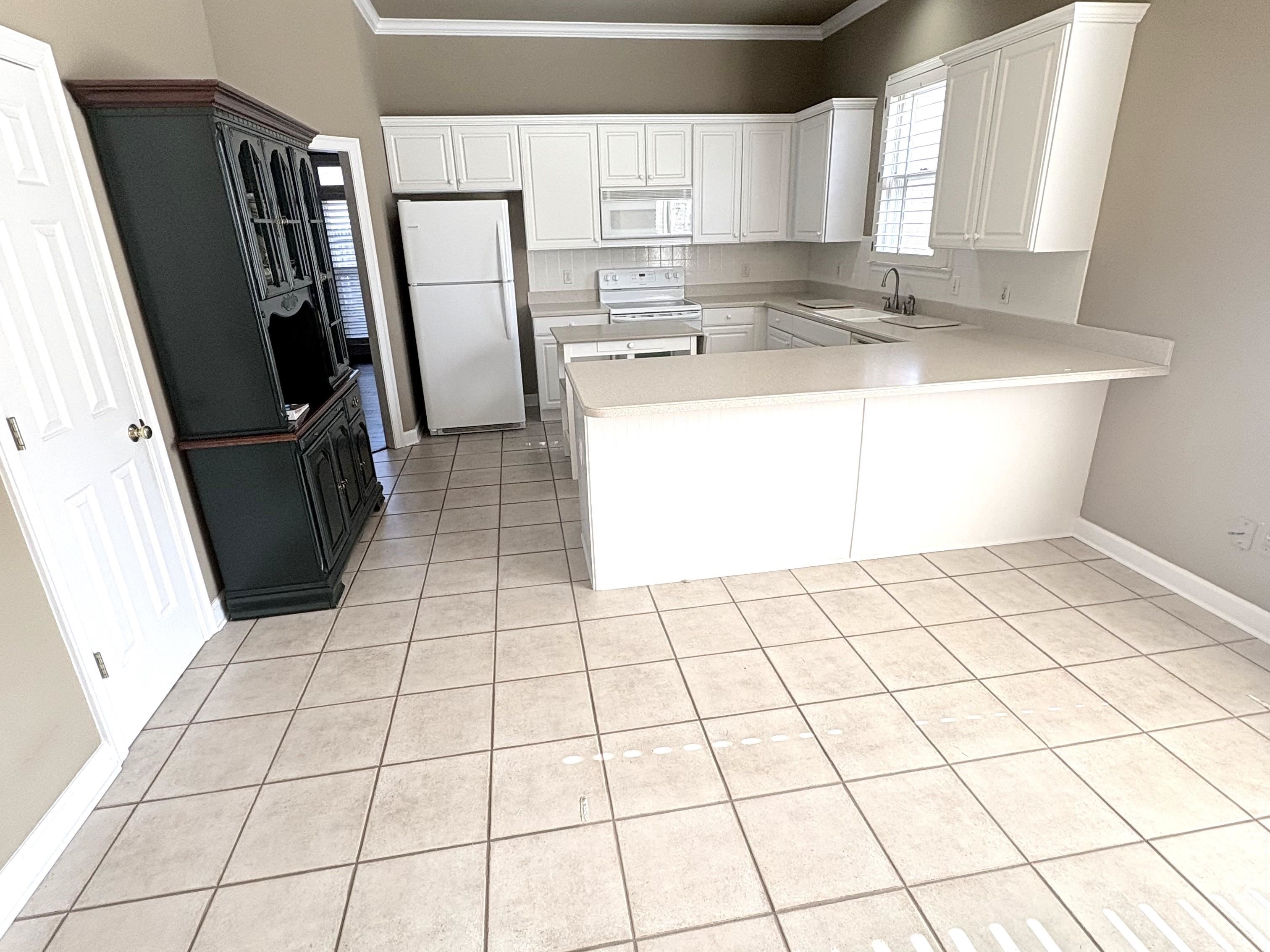 1740 Constable Court Collierville, TN 38017 - Photo 4 of 17 Kitchen with light countertops, white appliances, white cabinetry and peninsula.