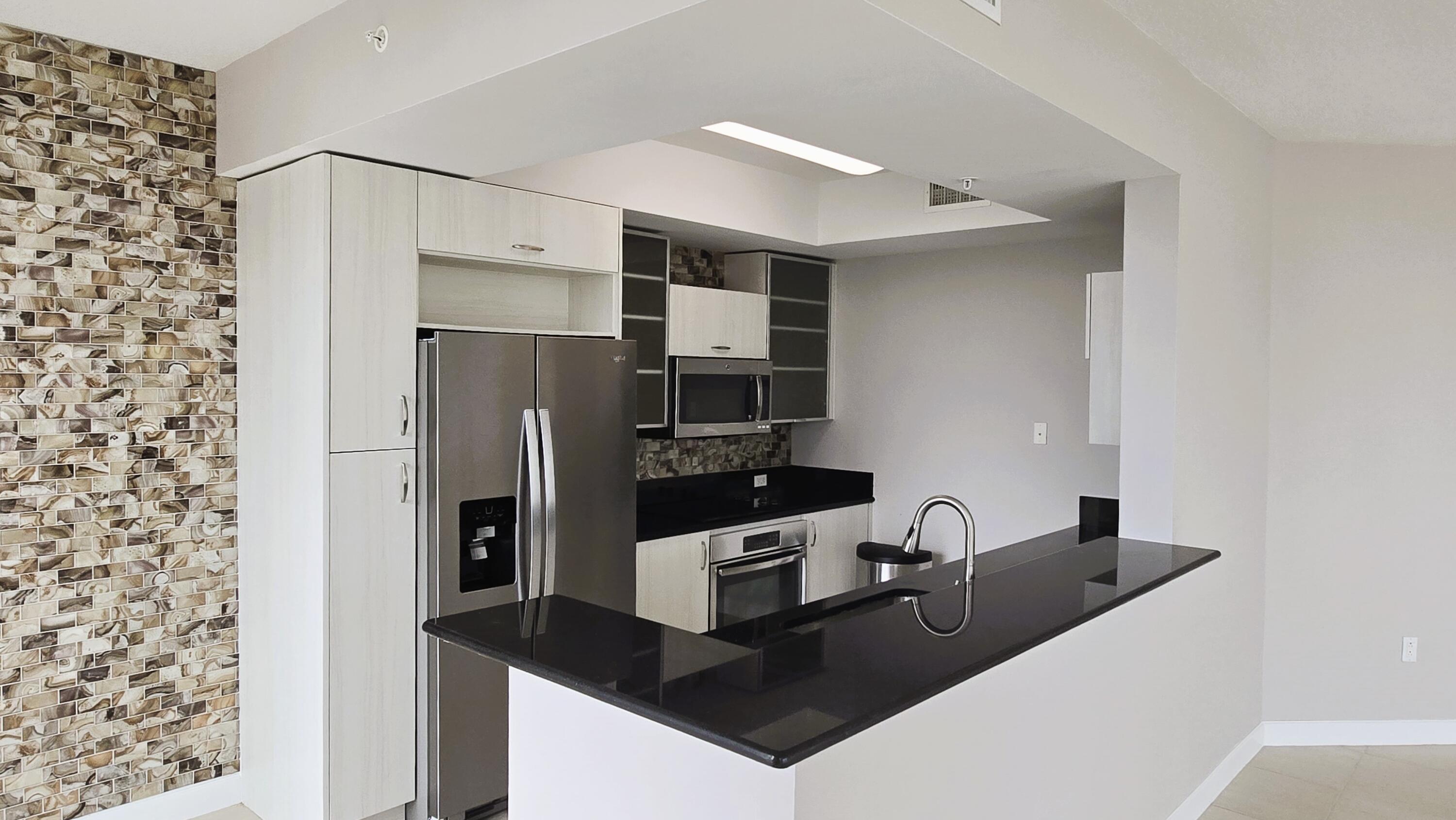 410 Evernia Street, Unit 701 West Palm Beach, FL 33401 - Photo 5 of 29 a kitchen with stainless steel appliances a sink and refrigerator