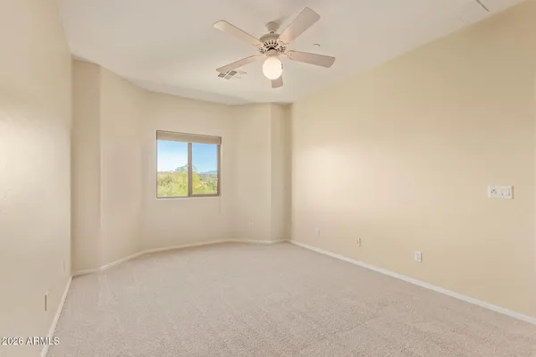 an empty room with a window and a fan
