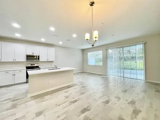 a large kitchen with kitchen island a sink stainless steel appliances and a chandelier