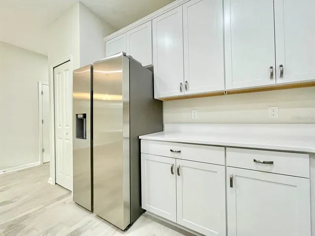 a kitchen with white cabinets and refrigerator