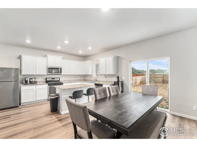 a kitchen with a dining table chairs and wooden floor