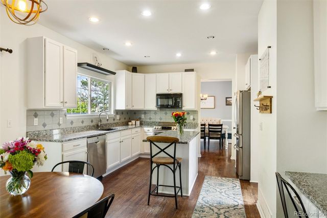a kitchen with sink refrigerator dining table and chairs