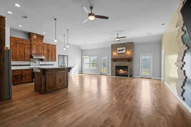a kitchen with stainless steel appliances granite countertop a refrigerator a stove top oven a sink dishwasher and a fireplace with wooden floor
