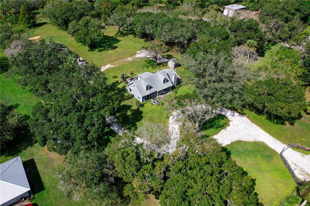 an aerial view of a house with a yard and large trees