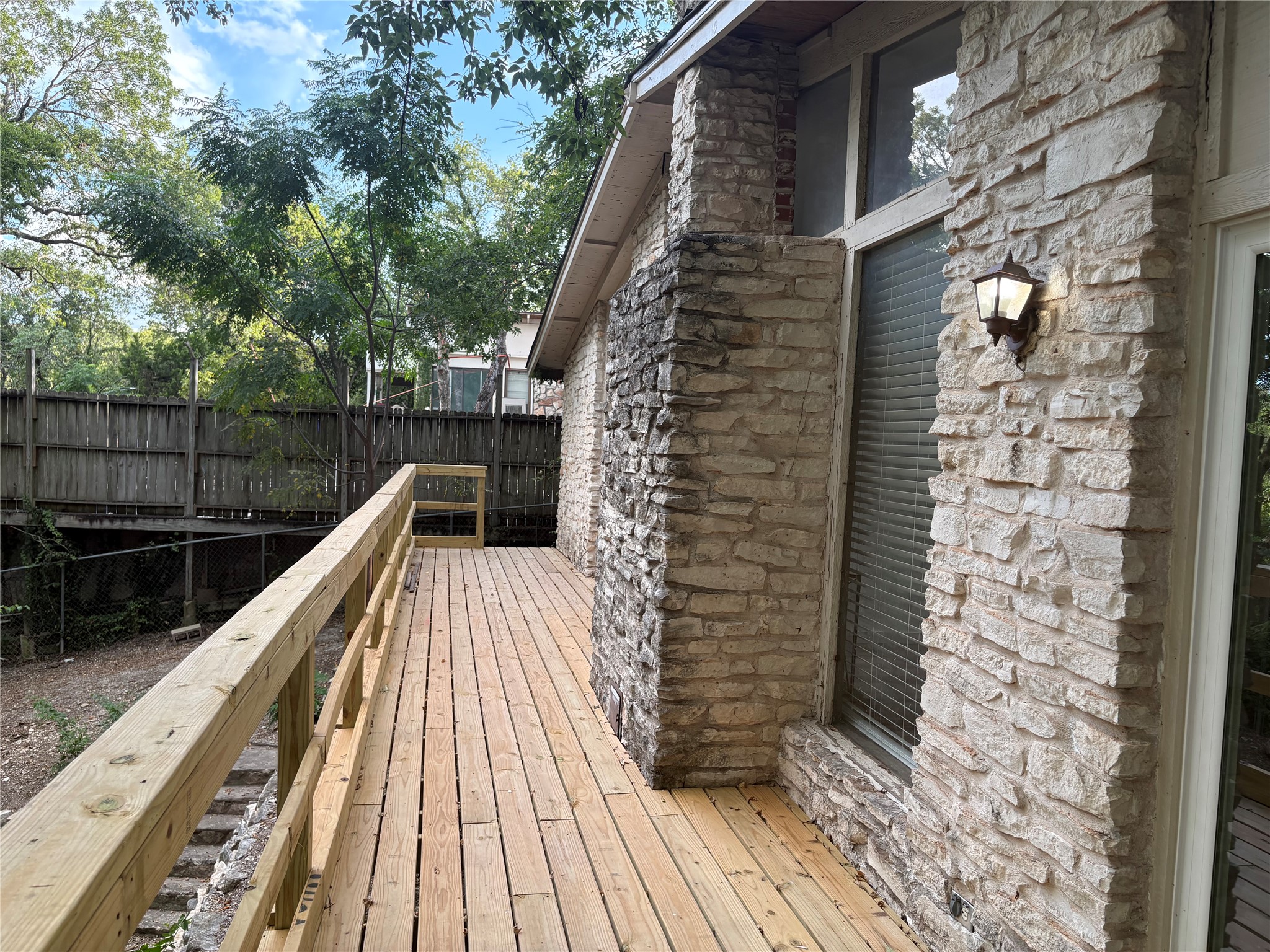 11913 Rennalee Loop Austin, TX 78753 - Photo 32 of 40 A newly constructed wood deck provides a serene outdoor living space, complementing the rustic stone and brick facade.