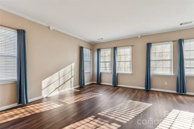 a view of an empty room with wooden floor and stairs