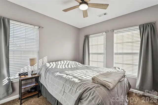 an empty room with chandelier fan and windows