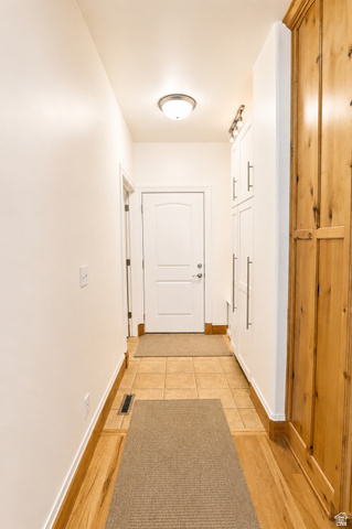 1055 North 1000 East Mapleton, UT 84664 - Photo 33 of 112 Hallway featuring wood-finish flooring, ceramic tile, white baseboards, and built-in white cabinetry with brushed nickel hardware