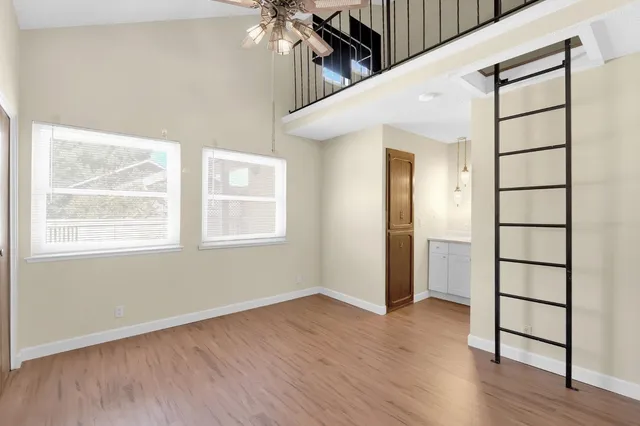 a view of an empty room with wooden floor and a window