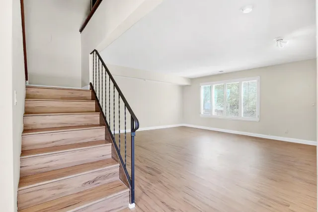 an empty room with wooden floor fireplace and windows