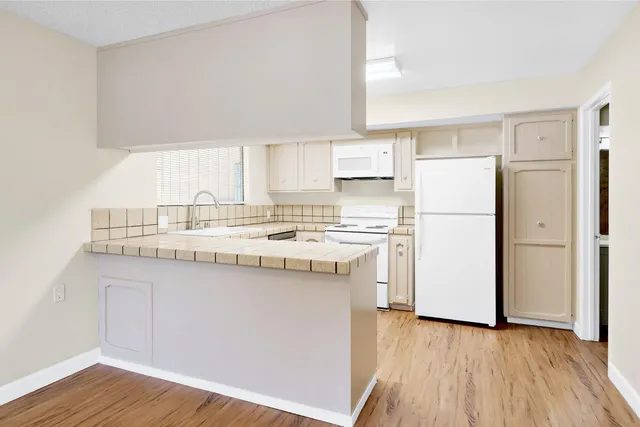a kitchen with stainless steel appliances granite countertop a sink and cabinets with wooden floor