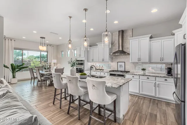 a kitchen with stainless steel appliances kitchen island granite countertop a stove a sink a dining table and chairs with wooden floor