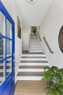 a view of staircase with lots of frames on wall and a potted plant