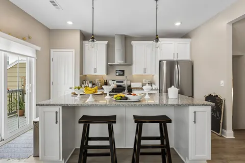 a kitchen with stainless steel appliances granite countertop a sink a stove a refrigerator and island with wooden floor