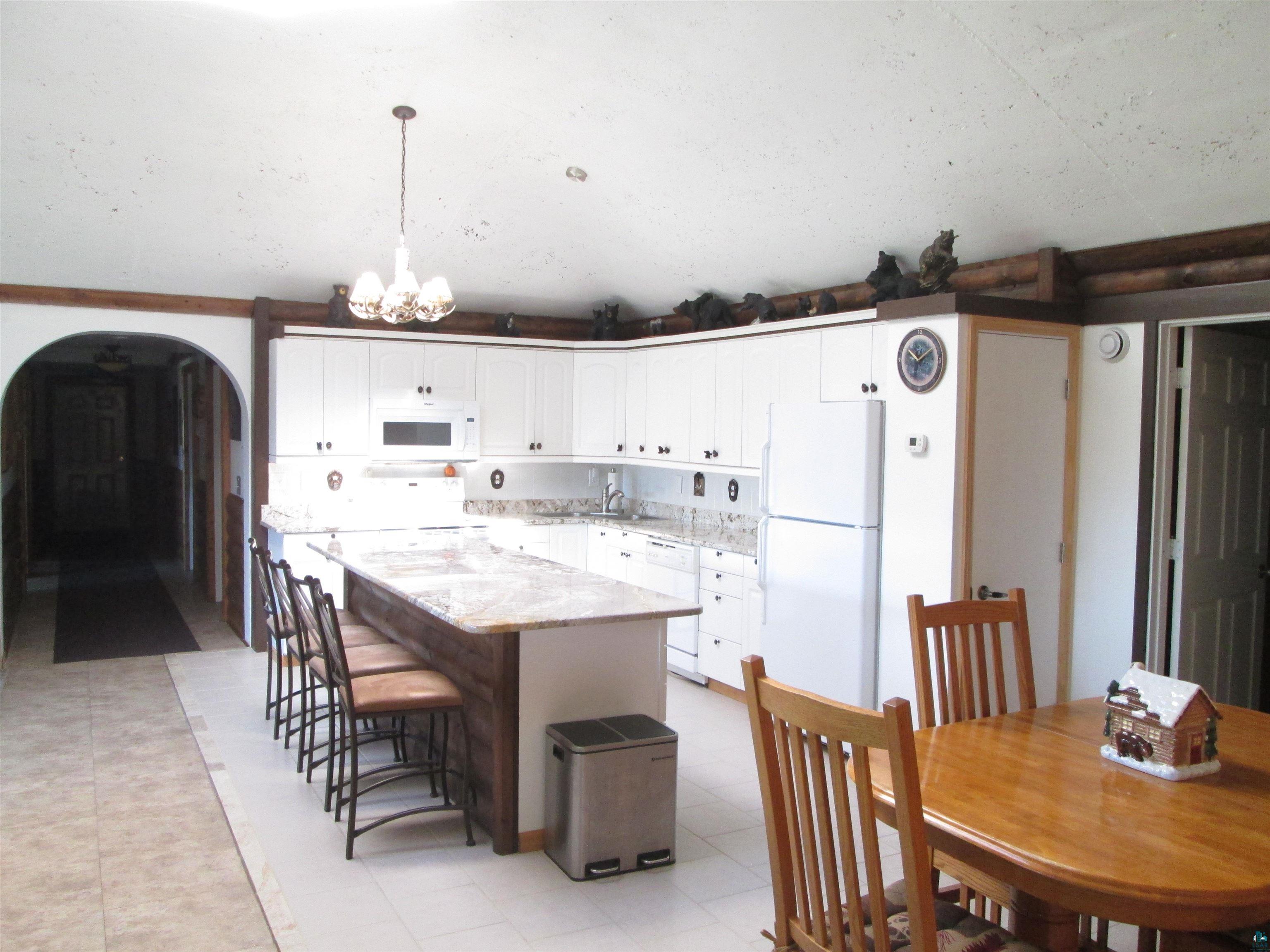 8882 Shortcut Road Lake Nebagamon, WI 54849 - Photo 12 of 47 Kitchen with white appliances, a kitchen island, arched walkways, and white cabinets