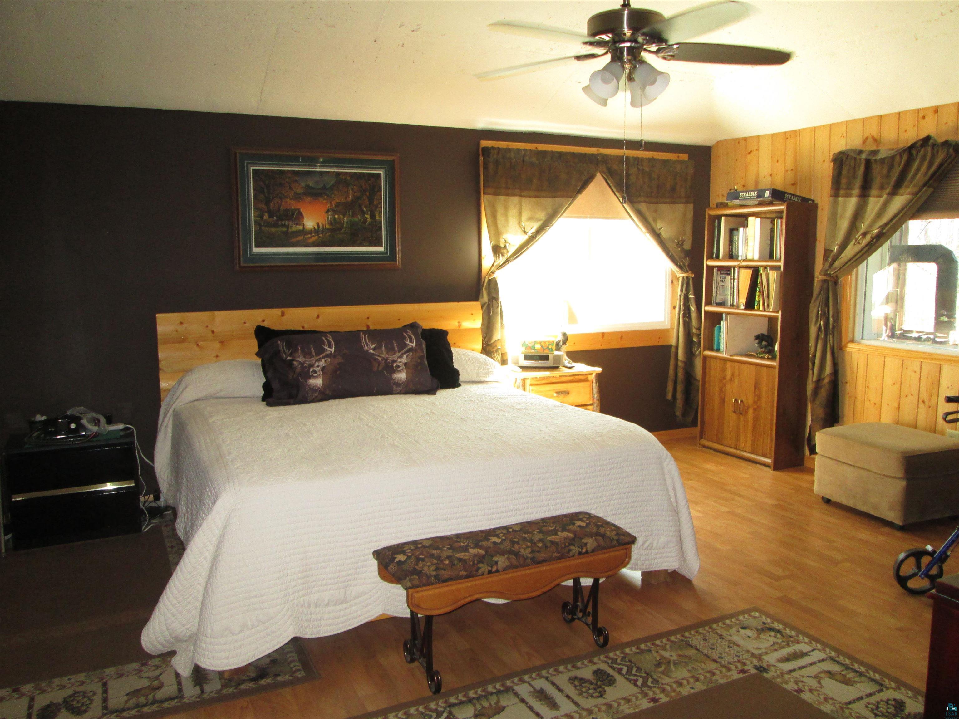 8882 Shortcut Road Lake Nebagamon, WI 54849 - Photo 17 of 47 Bedroom with light wood-style floors, wood walls, and a ceiling fan