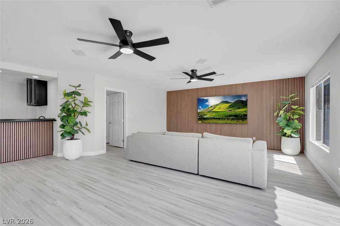 3604 North Campbell Road Las Vegas, NV 89129 - Photo 25 of 54 Living room featuring light wood-style floors, ceiling fan, an accent wall, baseboards, and wooden walls