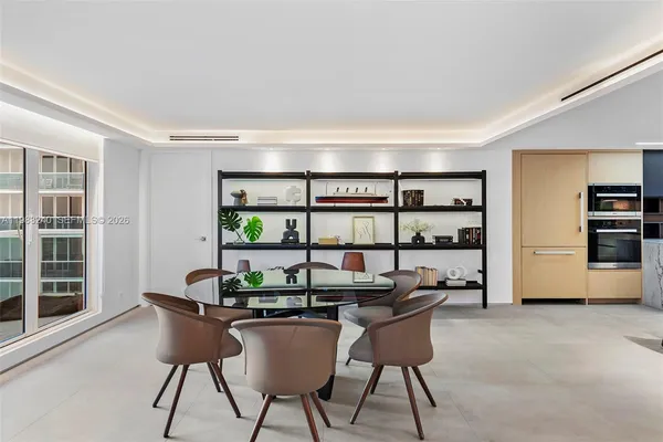a kitchen with stainless steel appliances granite countertop a sink a stove white cabinets and a dining table