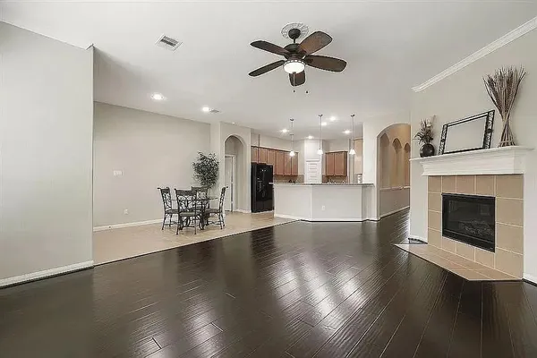 an empty room with wooden floor a ceiling fan a fireplace and windows