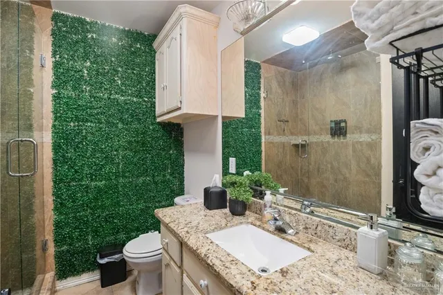 a bathroom with a granite countertop sink a toilet and shower
