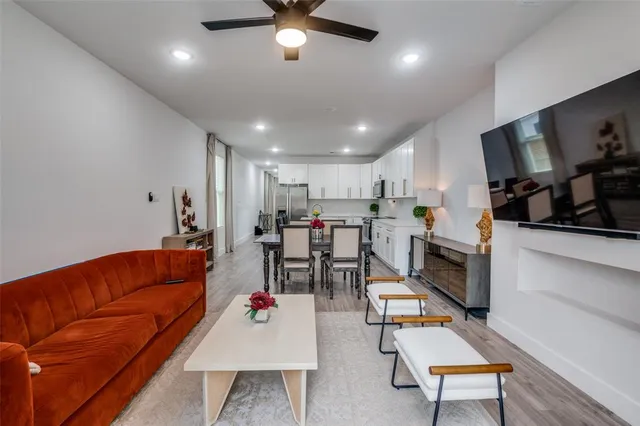 a living room with furniture kitchen view and a flat screen tv