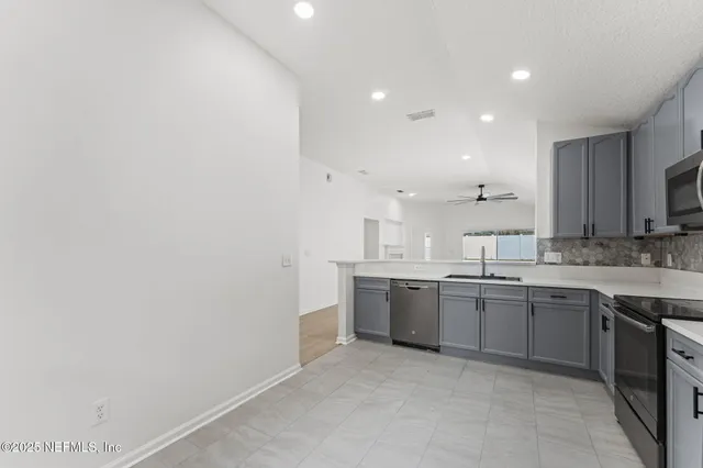 a large kitchen with a sink and dishwasher a stove with wooden floor