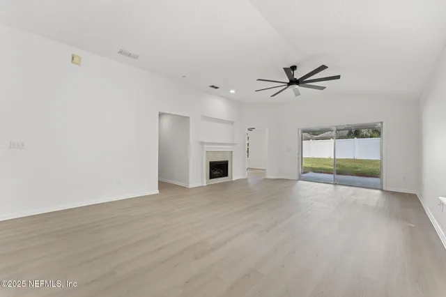 a view of empty room with a fireplace and wooden floor