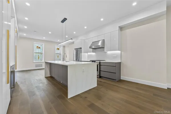 a large white kitchen with wooden floors and stainless steel appliances