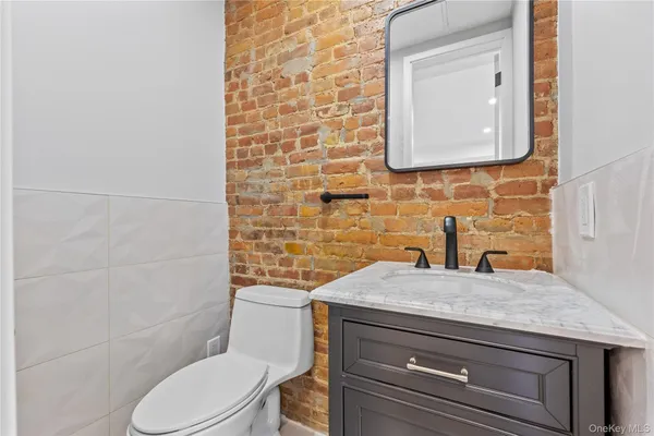 a bathroom with a granite countertop toilet sink and mirror
