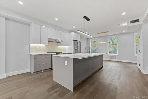 a large kitchen with a center island wooden floor and stainless steel appliances