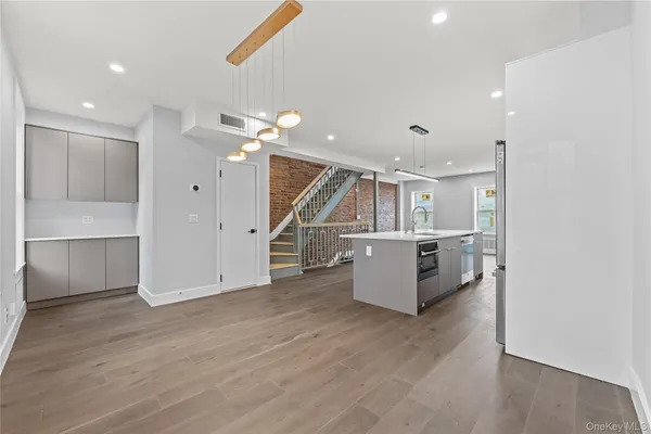 a view of an empty room with wooden floor and stairs