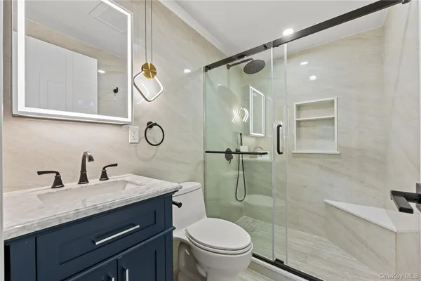 a bathroom with a granite countertop toilet sink and mirror