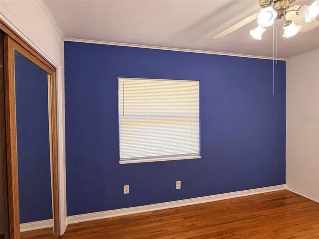 a view of empty room with wooden floor and fan