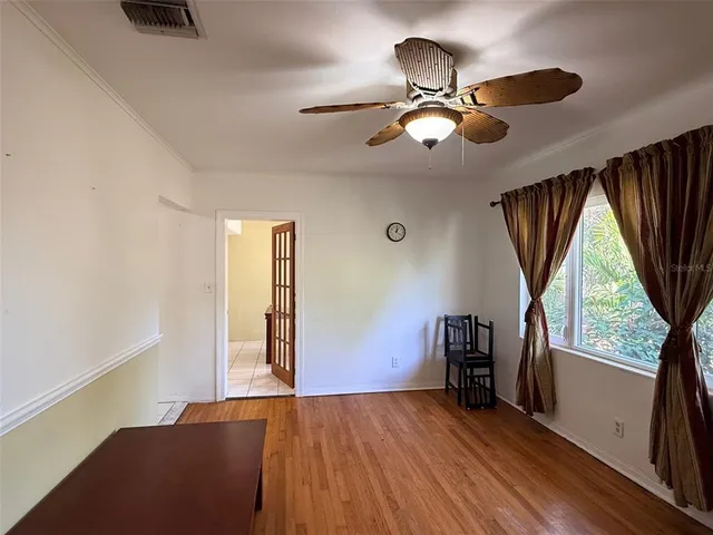 a view of empty room with wooden floor and fan