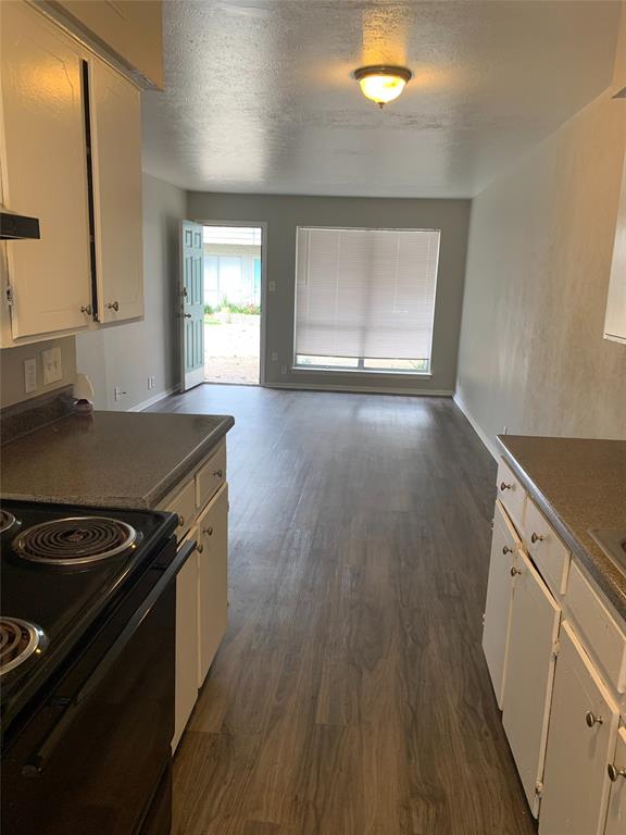 4606 Monarch Street, Unit 109 Dallas, TX 75204 - Photo 11 of 17 Kitchen featuring electric range, dark countertops, white cabinets, dark wood-style floors, and a textured ceiling