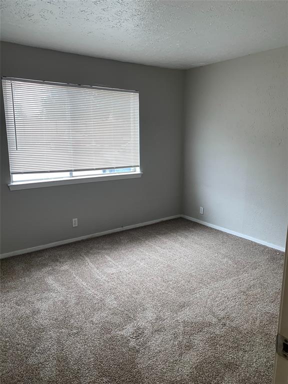 4606 Monarch Street, Unit 109 Dallas, TX 75204 - Photo 12 of 17 Carpeted spare room featuring a textured ceiling and baseboards