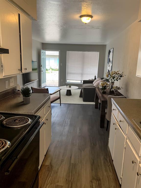 4606 Monarch Street, Unit 109 Dallas, TX 75204 - Photo 6 of 17 Kitchen featuring black / electric stove, white cabinets, dark countertops, a textured ceiling, and dark wood-style flooring