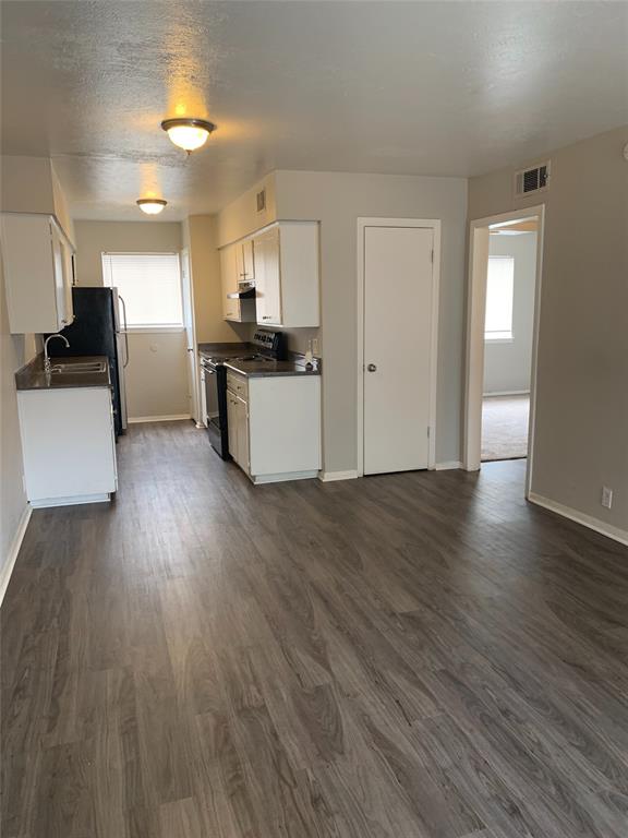 4606 Monarch Street, Unit 109 Dallas, TX 75204 - Photo 9 of 17 Kitchen featuring dark countertops, black range oven, dark wood-type flooring, white cabinets, and a textured ceiling