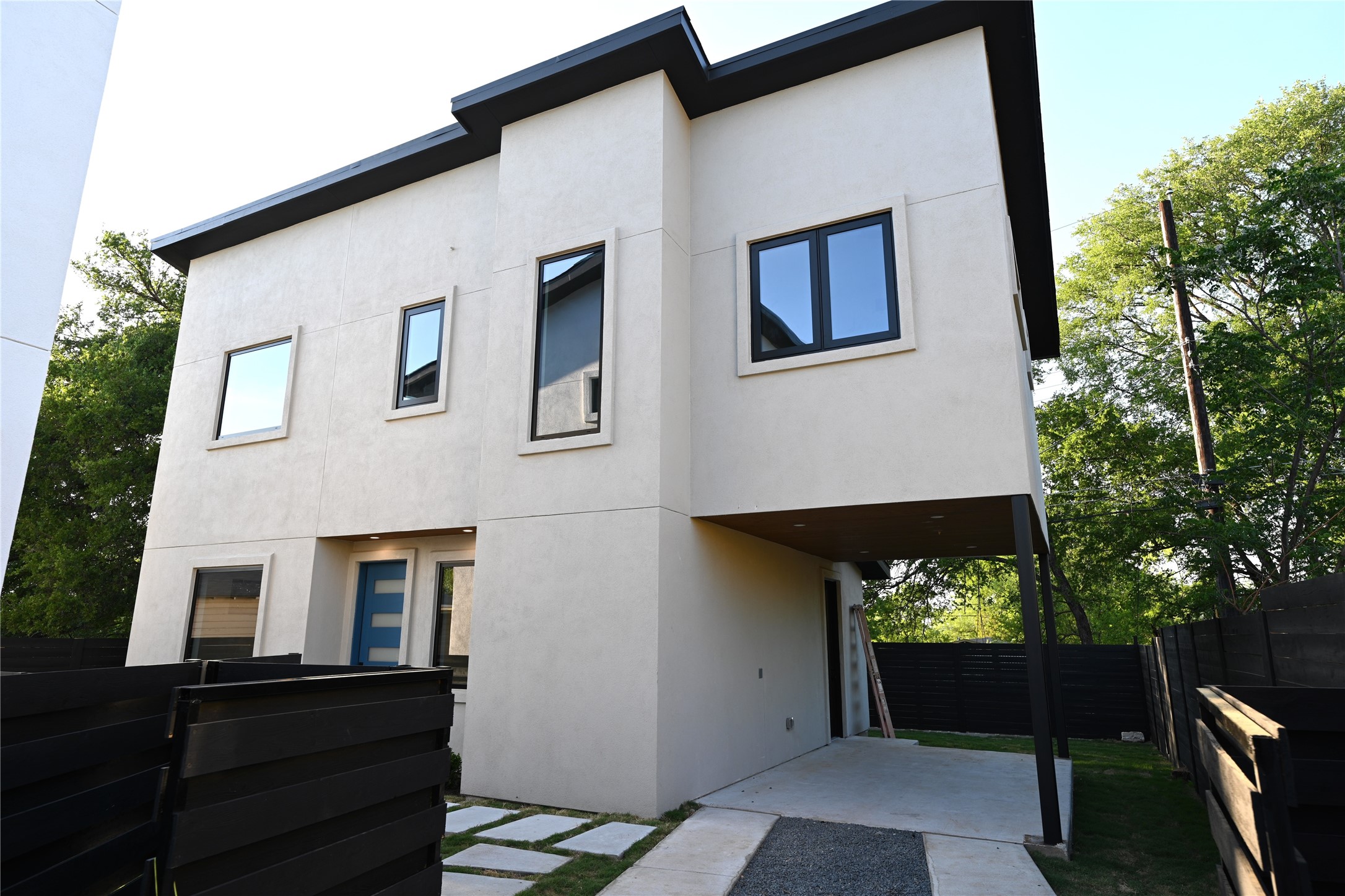 4410 Glomar Avenue, Unit 2 Austin, TX 78721 - Photo 1 of 24 The property presents a contemporary exterior with light-colored stucco, black-framed windows, and a distinctive blue front door, private fence and automatic gate