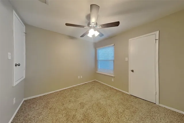 an empty room with a chandelier fan and closet