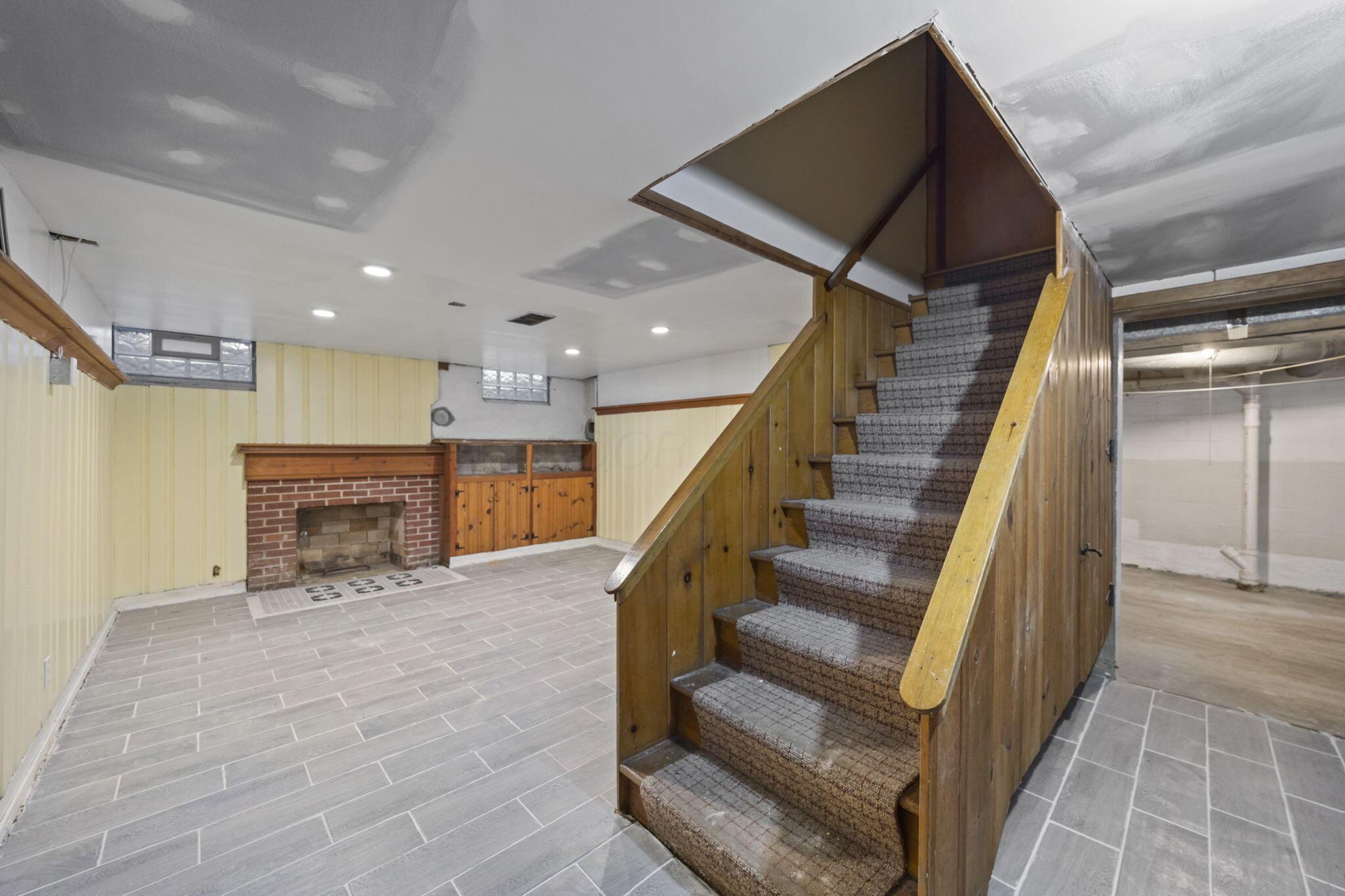 40 South Kellner Road Columbus, OH 43209 - Photo 32 of 57 Finished basement with tile flooring, brick fireplace, built-in cabinetry, and paneled walls