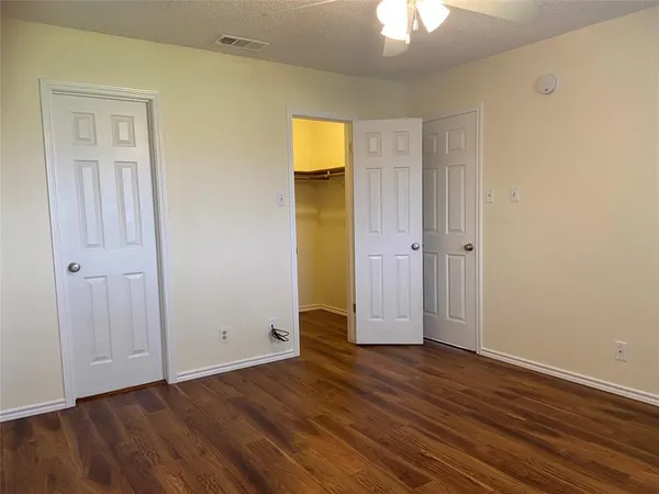 an empty room with wooden floor and a ceiling fan